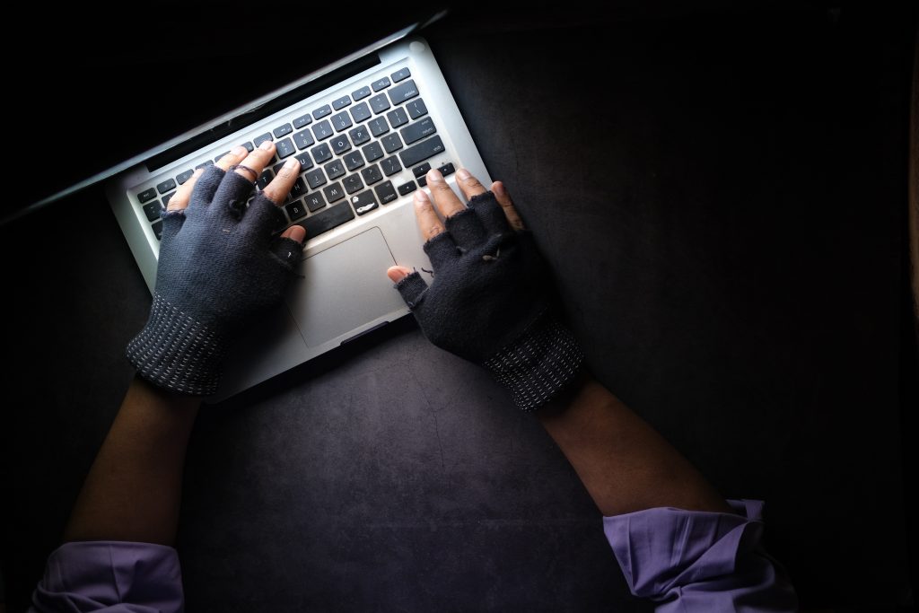 a pair of gloved hands on a laptop keyboard insinuating illicit activity